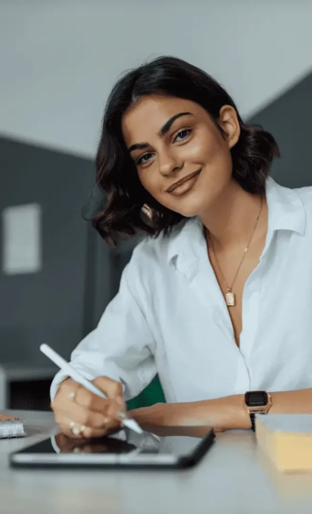 Une femme professionnelle dans le secteur IT travaille sur son iPad tout en souriant.